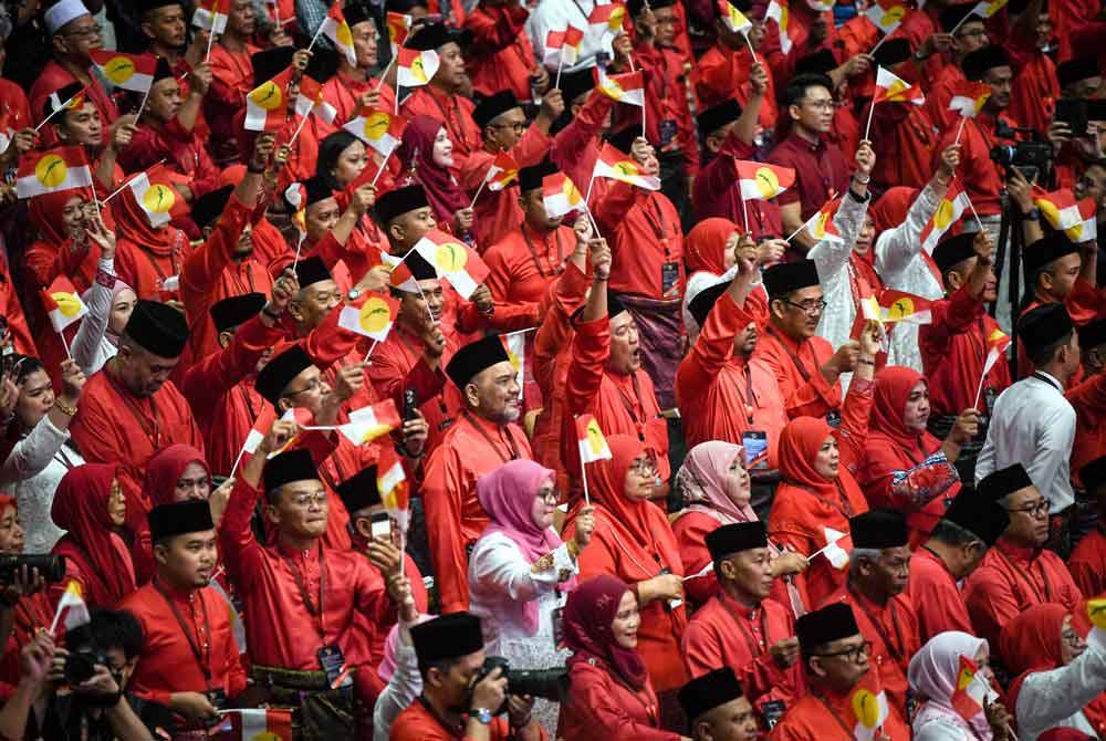 Para perwakilan bersemangat mengibarkan bendera UMNO semasa Perhimpunan Agung UMNO 2023.