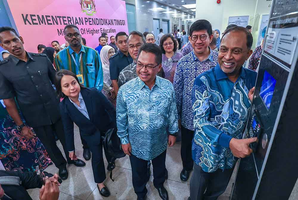 Zambry mengimbas jari pada mesin perakam waktu pada hari pertamanya di Kementerian Pendidikan Tinggi sebagai Menteri sambil disaksikan oleh Mustapha (tiga dari kanan) pada Khamis. - Foto Bernama