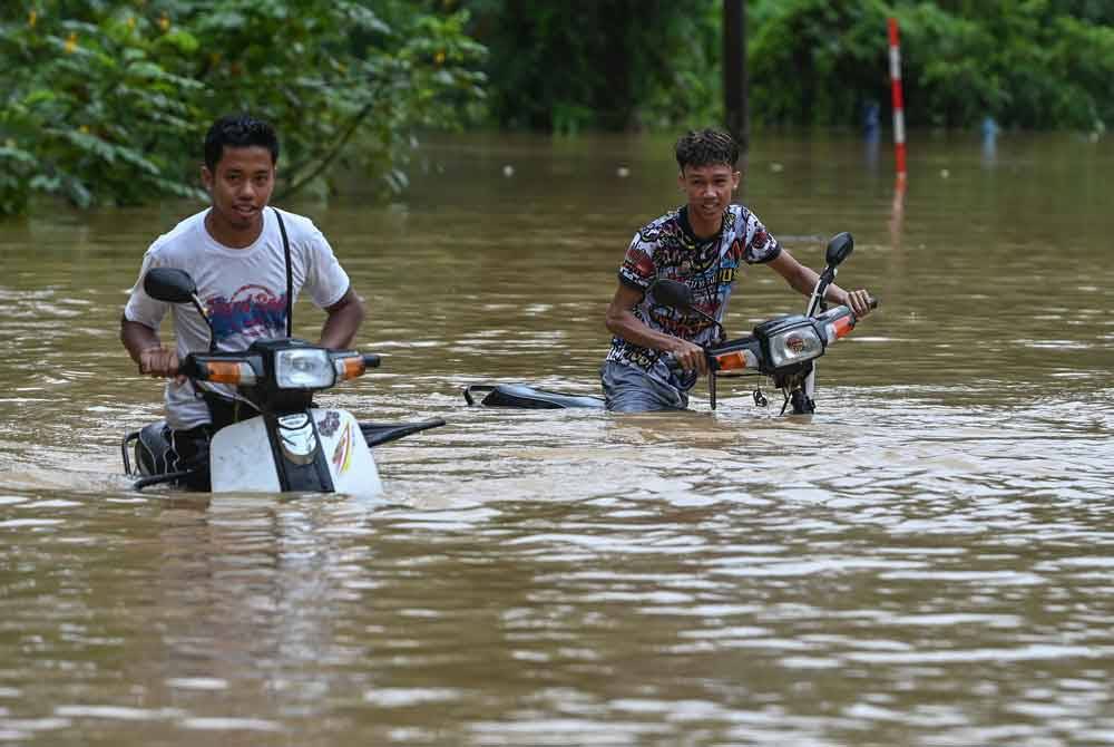 Sebahagian penduduk meredah banjir dengan menaiki motosikal selepas kawasan berkenaan dinaiki air ketika tinjauan di Kampung Pengkalan Ajal pada Khamis. - Foto Bernama