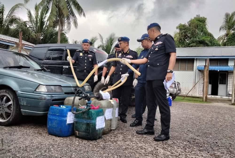 Azman menunjukkan alat yang digunakan untuk mengepam diesel dari tangki kenderaan ke tong.