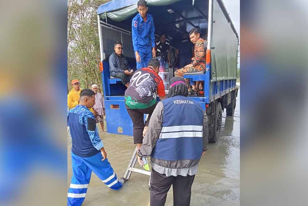 Anggota penyelamat membantu memindahkan penduduk yang terjejas banjir. - Foto APM