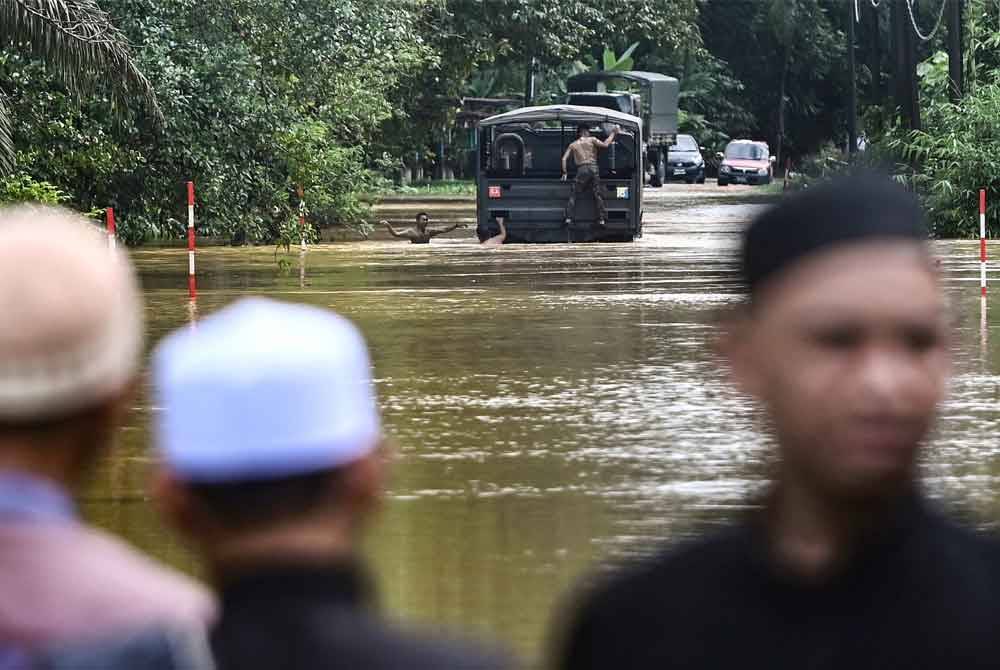 Sebuah kenderaan milik ATM meredah banjir ketika tinjauan di Kampung Pengkalan Ajal, pada Jumaat. - Foto Brnama