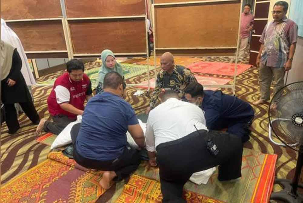 Sekumpulan jemaah membantu menguruskan jenazah Latipah Yusof yang meninggal dunia ketika solat Asar di surau di sebuah hotel di Sungai Petani, pada Sabtu. - Foto ihsan PDRM