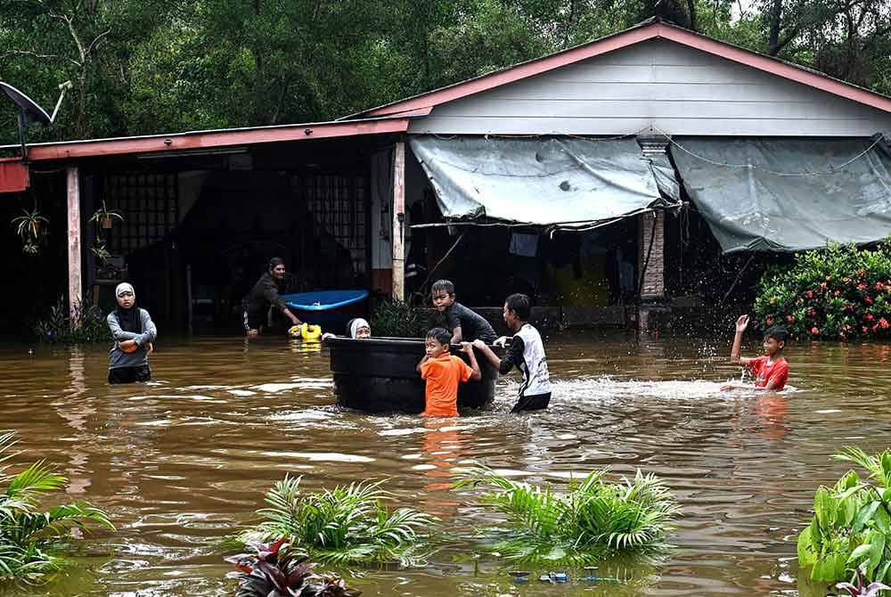 Gelagat sekumpulan kanak-kanak bermain selepas kawasan rumahnya dinaiki air akibat hujan lebat ketika tinjauan di Kampung Paya, Balai Besar pada Sabtu. - Foto Bernama