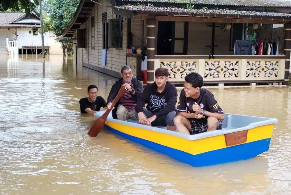 Syukri (dua dari kiri) bersama bot fiber yang dibeli bagi membantu proses perpindahan ke lokasi selamat.