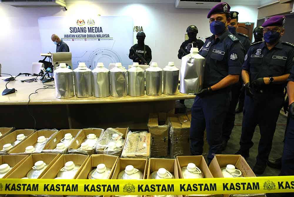 Sazali (depan) menunjukkan botol aluminium berisi dadah jenis Fentanyl yang dirampas