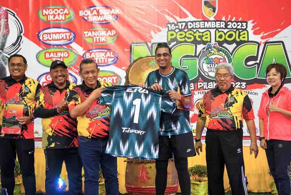 Menteri Besar Negeri Sembilan Datuk Seri Aminuddin Harun (tiga, kiri) menerima jersi pasukan dari wakil penyampai radio Era FM, Azad Jasmin (tiga, kanan) pada Pesta Bola Ngoca 2023 di Stadium Ngoca Perkampungan Budaya Terachi, pada Ahad. - Foto Bernama