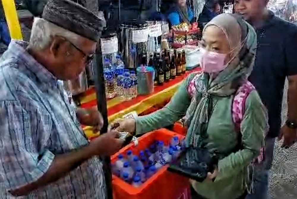 Pegawai JPN Melaka (kiri) memeriksa kad pengenalan orang awam di Uptown Dataran Klebang.