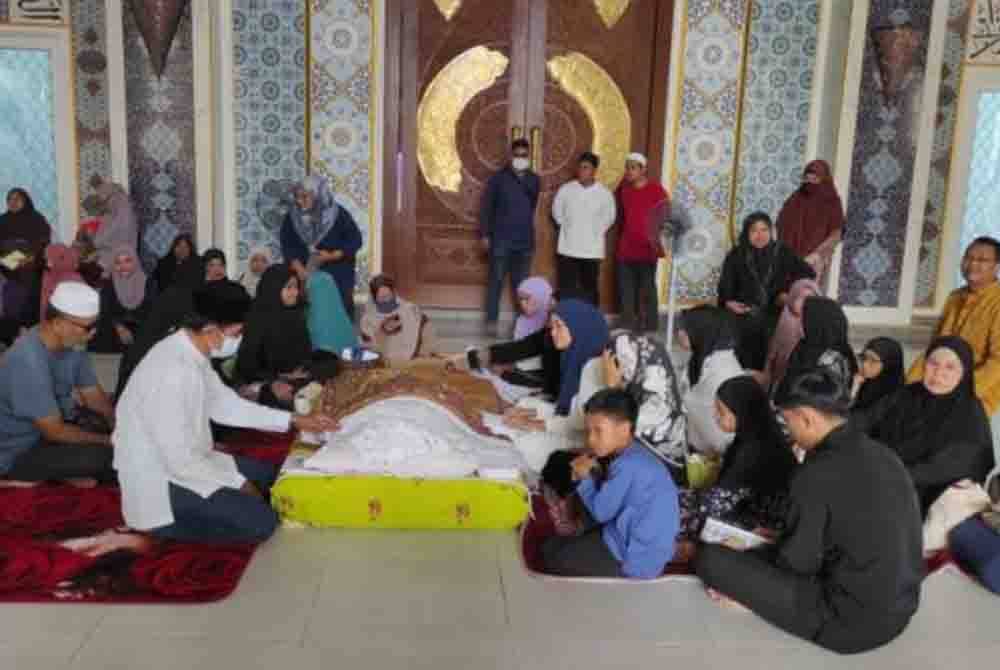 Ahli keluarga Allahyarham setia mendampingi jenazah Allahyarham Datuk M. Daud Kilau sambil membacakan ayat-ayat suci al-Quran di Masjid Tuminah Hamidi, Bagan Datuk, pada Selasa. - Foto Awani