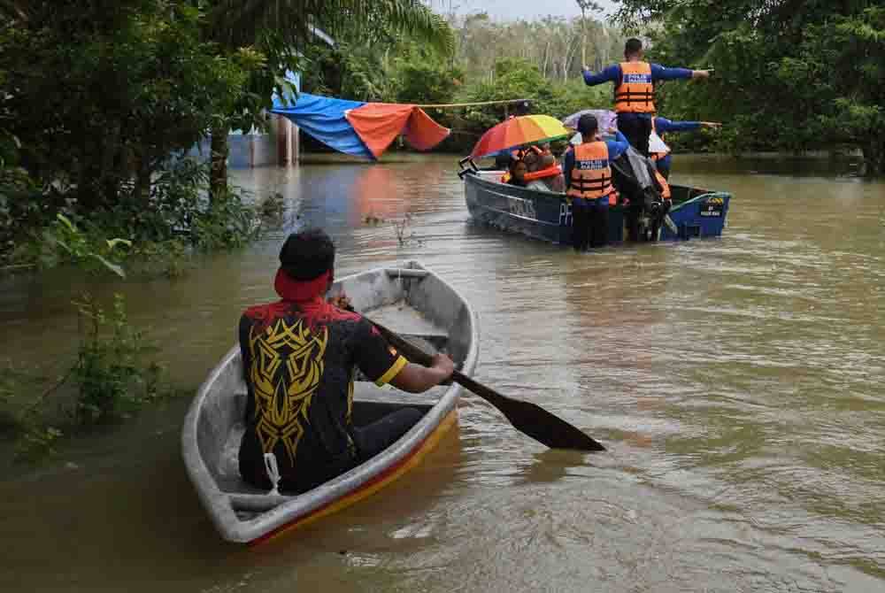 Anggota IPD Pasir Mas membantu memindahkan penduduk Kampung Serongga ke Pusat Pemindahan Sementara (PPS) Sekolah Kebangsaan Sri Kiambang berikutan kediaman mereka dilanda banjir. - Foto Bernama