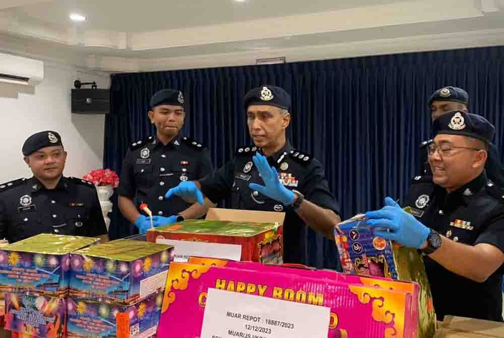 Raiz Mukhliz (tengah) bersama sebahagian mercun yang dirampas. - Foto IPD Muar