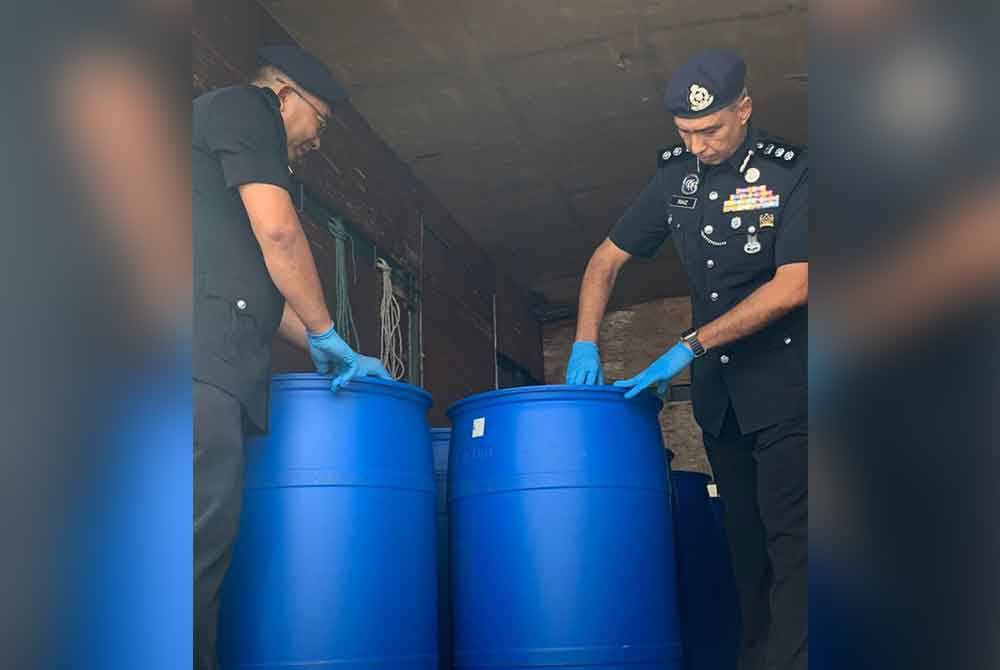 Raiz Mukhliz (kanan) memeriksa tong yang disyaki mengandungi cecair parti arak. - Foto: IPD Muar