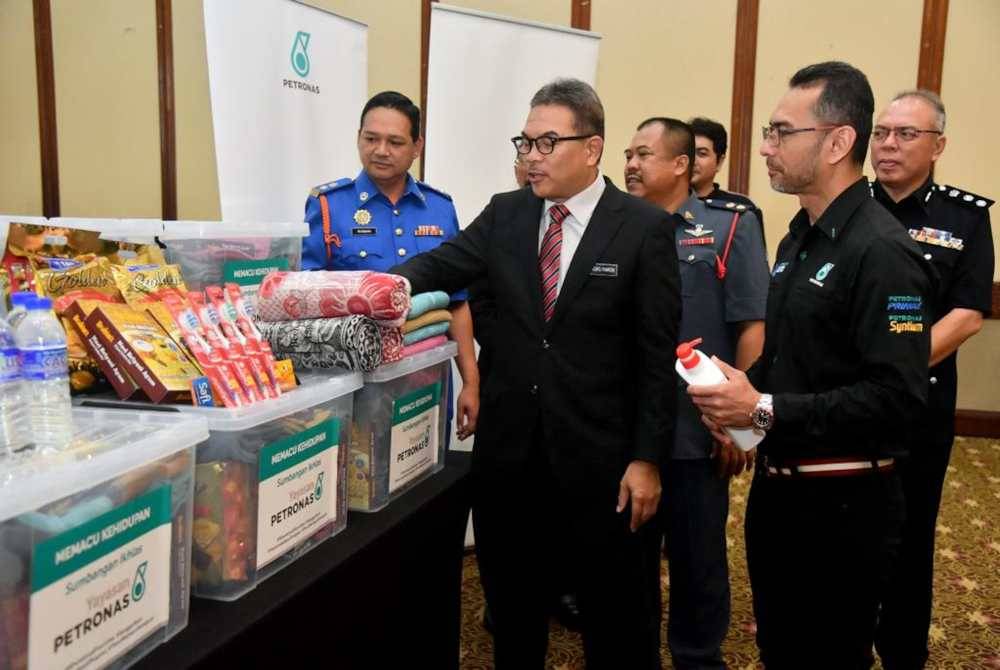 Tengku Farok (dua dari kiri) bersama Mohammad Ahmad Shazly (kanan) melihat sebahagian kit bantuan banjir yang diagihkan sempena Program Memacu Kehidupan: Bantuan Bencana 2023 di Kuala Terengganu.