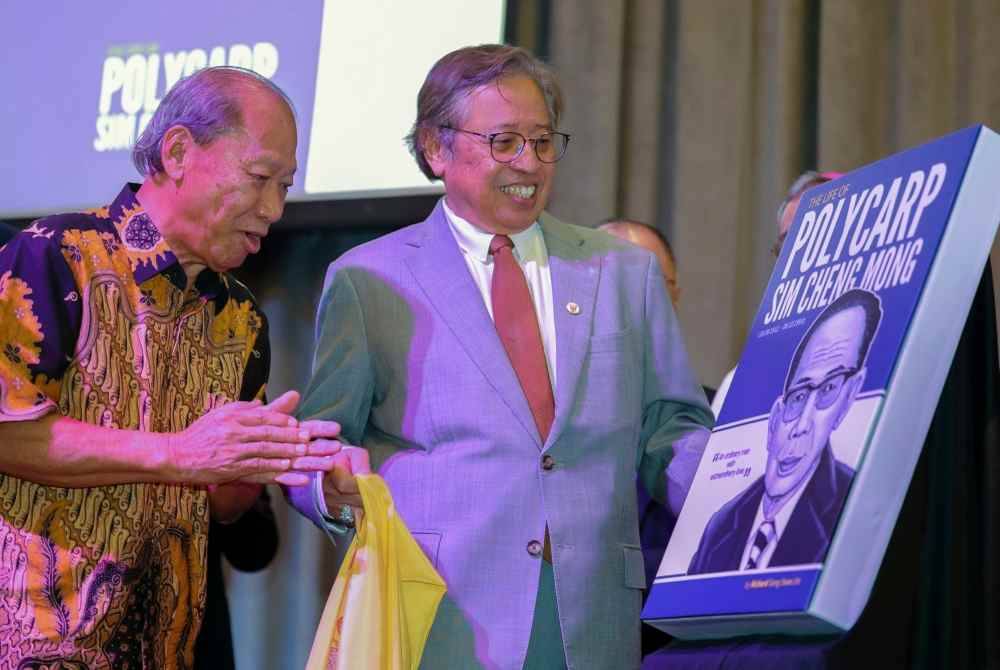 Abang Johari (kanan) ketika melancarkan buku biografi Datuk Polycarp Sim Cheng Mong hari ini. Turut hadir pengarang buku tersebut, Richard Song Swee Jin (kiri). - Foto Bernama