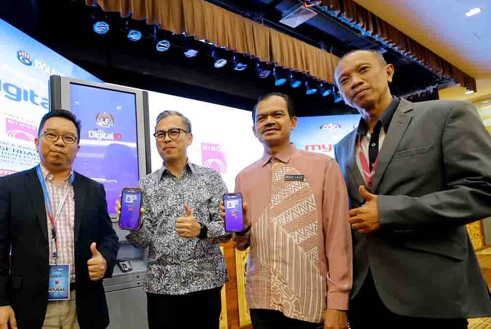 Fahmi (dua dari kiri) bersama Ketua Setiausaha Kementerian Komunikasi, Datuk Mohamad Fauzi Md Isa (dua dari kanan) menunjukkan MyDigital ID semasa hadir ke Sesi Pendaftaran MyDigital ID Kementerian Komunikasi dengan kerjasama MIMOS di Kementerian Komunikasi, pada Khamis. - Foto Bernama