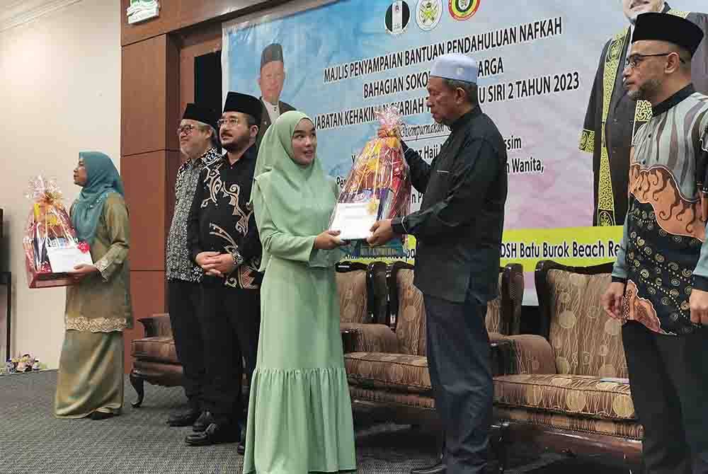 Maliaman (dua dari kanan) menyampaikan Bantuan Pendahuluan Nafkah Bahagian Sokongan Keluarga Jabatan Kehakiman Syariah Terengganu Siri 2 Tahun 2023 kepada seorang penerima di Kuala Terengganu pada Khamis.