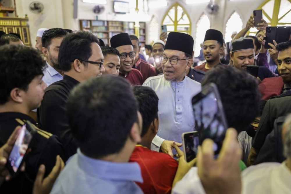 Anwar menyantuni para jemaah selepas menunaikan solat Jumaat di Masjid Kota Damansara, hari ini. - Foto Bernama