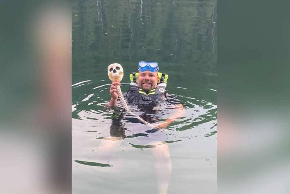 Pegawai WDFW, Severin Erickson memegang bong atau corong plastik bir berbentuk tengkorak selepas menyelam di kawasan gua di Sungai Pend Oreille, Idaho. - Agensi