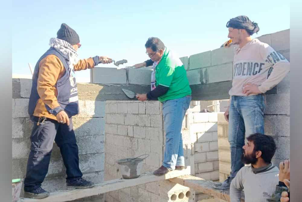 Dr Mohd Zin (kiri) dan Mas Imran mengikat batu sebuah rumah dalam pembinaan untuk pelarian di bandar Albab, Syria pada Jumaat.