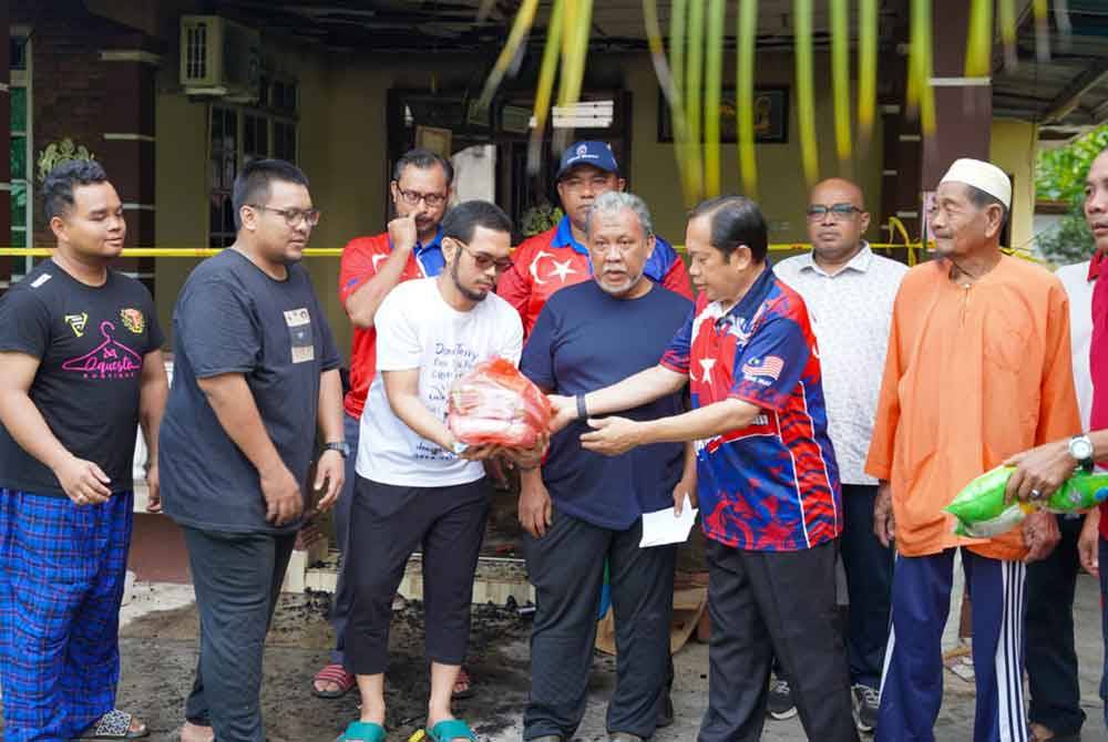 Ahmad (dua dari kanan) melawat rumah mangsa kebakaran R Azmi @ Adon Abdul Rahman di Kampung Parit Wak Jabir di Benut.