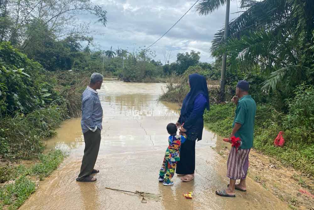 Penduduk melihat Jambatan Pasir Jering yang ditenggelami air akibat hujan lebat.