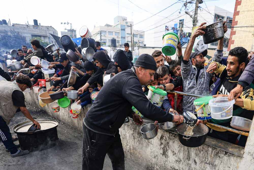 Proses agihan makanan dilakukan di sebuah kem penempatan sementara di Rafah di selatan Genting Gaza pada Sabtu. - Foto AFP