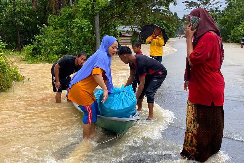 Nurisan membantu suaminya yang berjaya keluar selepas terperangkap di rumahnya di Kampung Gual Mekong, Rantau Panjang.