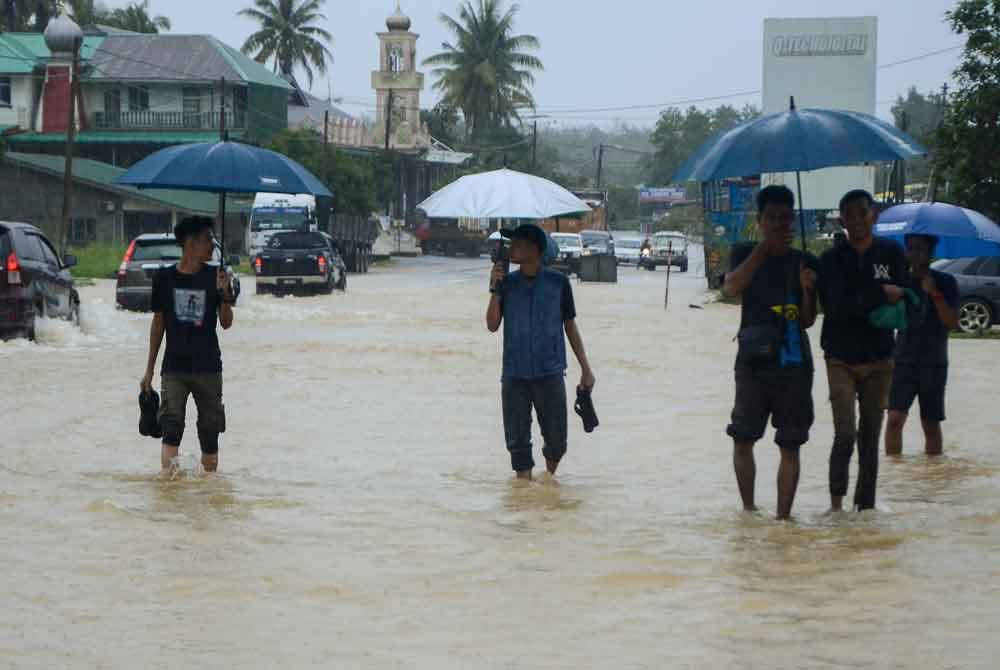 Penduduk meredah banjir yang melimpahi Jalan Jedok-Jeli berikutan hujan lebat sejak malam tadi ketika tinjauan di Kampung Kelewek pada Isnin. - Foto Bernama