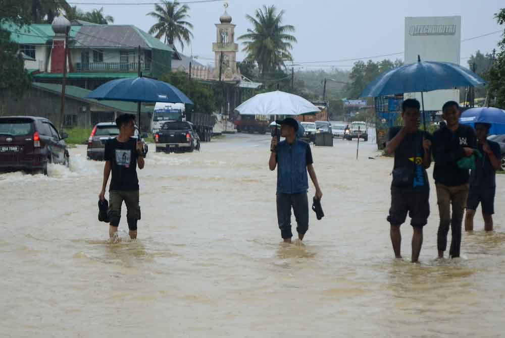 Penduduk meredah banjir yang melimpahi Jalan Jedok-Jeli berikutan hujan lebat sejak malam tadi ketika tinjauan di Kampung Kelewek hari ini. - Foto Bernama