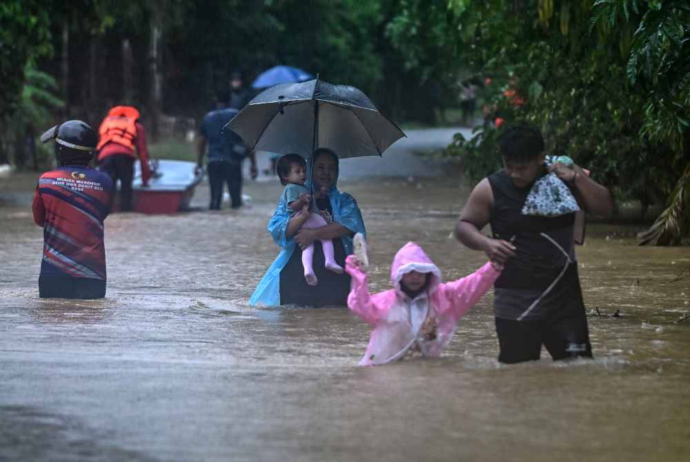 
Penduduk meredah air bah dengan membawa barangan keperluan untuk ke tempat lebih selamat selepas kawasan berkenaan dinaiki air ketika tinjauan di Kampung Belimbing Jongok Batu. Foto Bernama