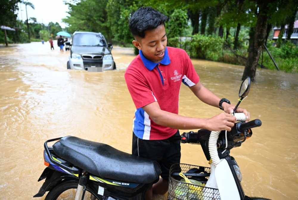 Muhammad Hanif Azhar menunjukkan hos mesin basuh pada motosikalnya supaya kenderaan itu dapat digerakkan ketika meredah banjir.