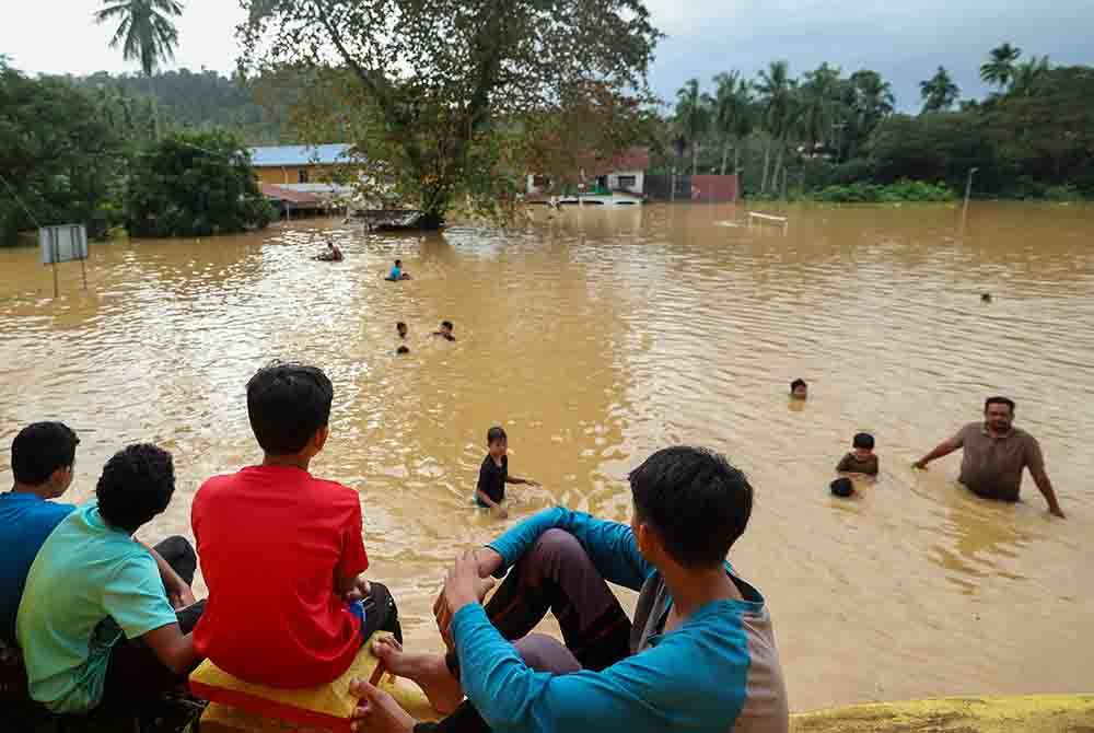 Kanak-kanak sedang asyik bermain air di sekitar Kampung Manek Urai yang dilanda banjir pada Selasa. - Foto Bernama