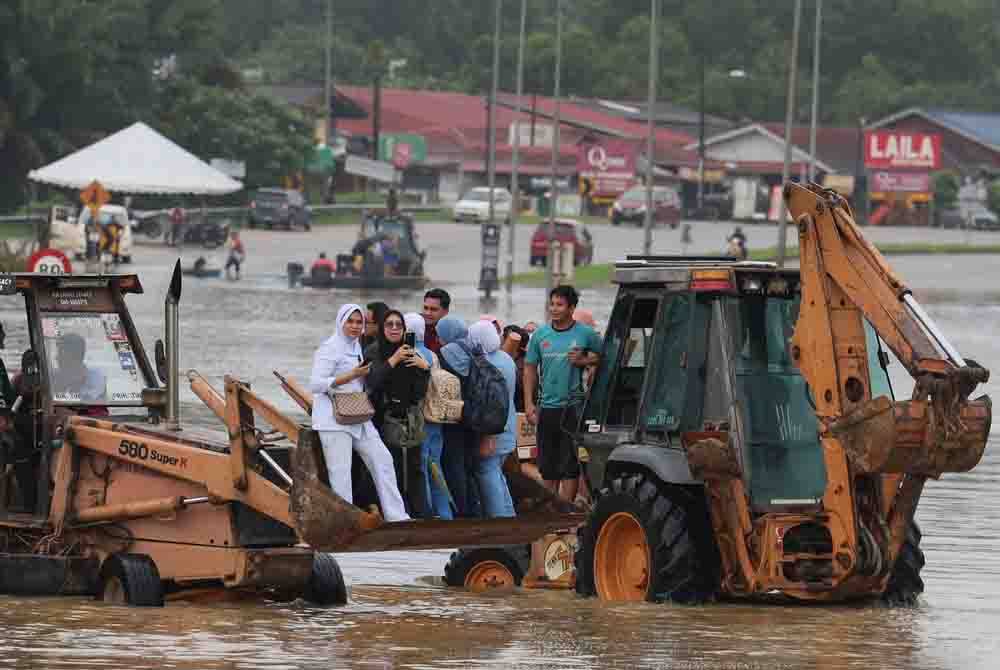 Kakitangan Hospital Hulu Terengganu menaiki jengkaut untuk pulang ke rumah selepas laluan utama Ajil- Kuala Berang terputus berikutan banjir pada tinjauan hari ini. - Foto Bernama