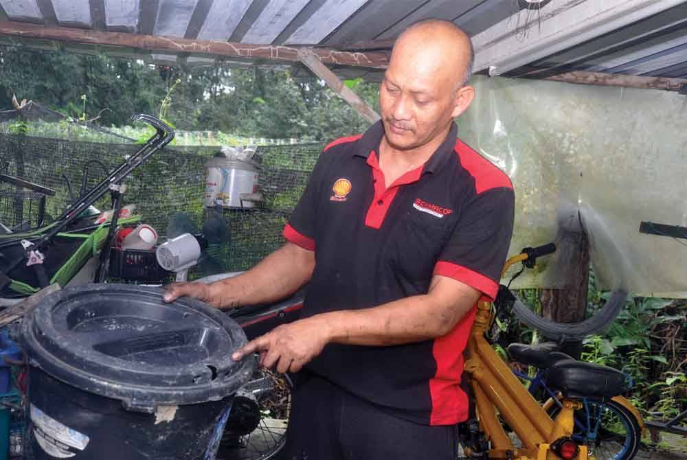 Mohd Azmi menunjukkan tong berisi makanan kucing yang berlubang kesan kuku beruang yang diselongkar haiwan buas itu di dalam stor belakang rumah di Kampung Padang Tapong pada Isnin malam. - Foto Bernama