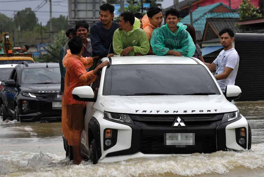 Penduduk terpaksa menggunakan kenderaan pacuan empat roda untuk melalui kawasan banjir.