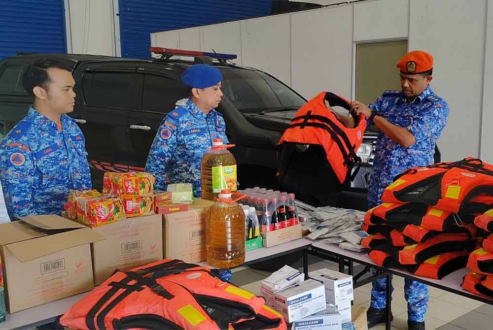 Che Adam (kanan) meninjau antara barangan yang disumbangkan pelbagai pihak kepada mangsa banjir melalui Pusat Pengumpulan Barangan Sumbangan Bencana Pantai Timur di Pejabat APM Pahang.