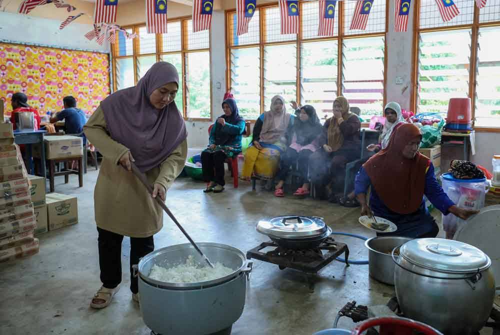 Nurul Fadilah (kiri) menyediakan nasi untuk makanan tengah hari semasa tinjauan di PPS Sekolah Menengah Kebangsaan Menerong, Ajil pada Khamis. - Foto Bernama