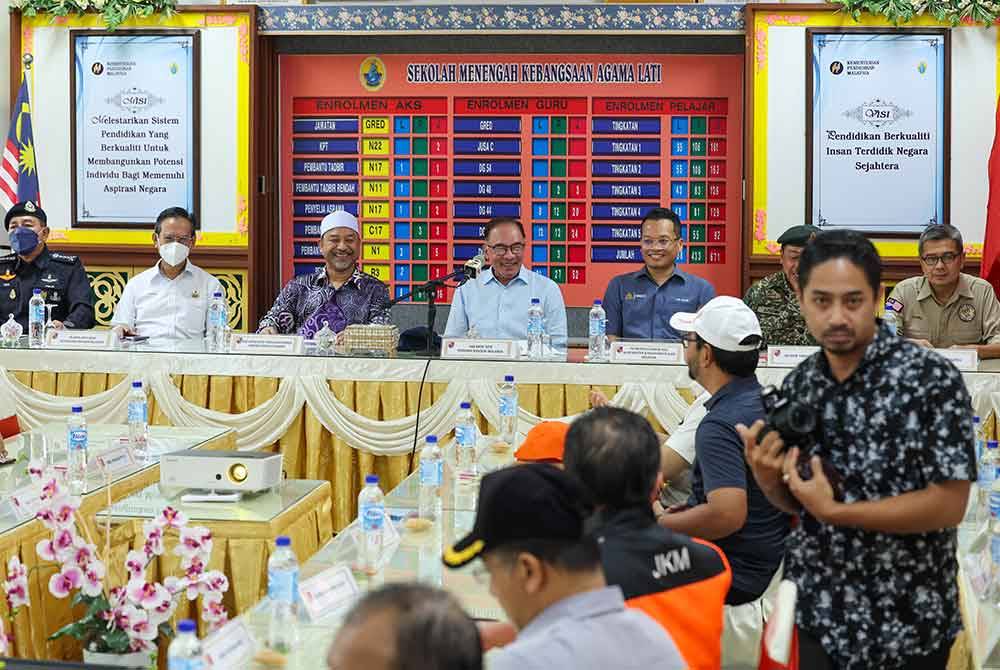 Anwar Ibrahim (empat dari kiri) menyertai mesyuarat tertutup ketika melawat mangsa banjir yang ditempatkan di PPS SMK Agama Lati di Pasir Mas, Kelantan. - Foto Bernama