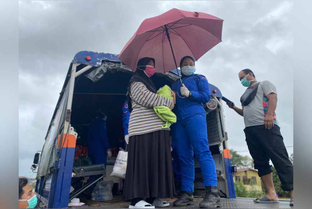 Anggota penyelamat membantu memindahkan penduduk yang terjejas banjir. Foto APM