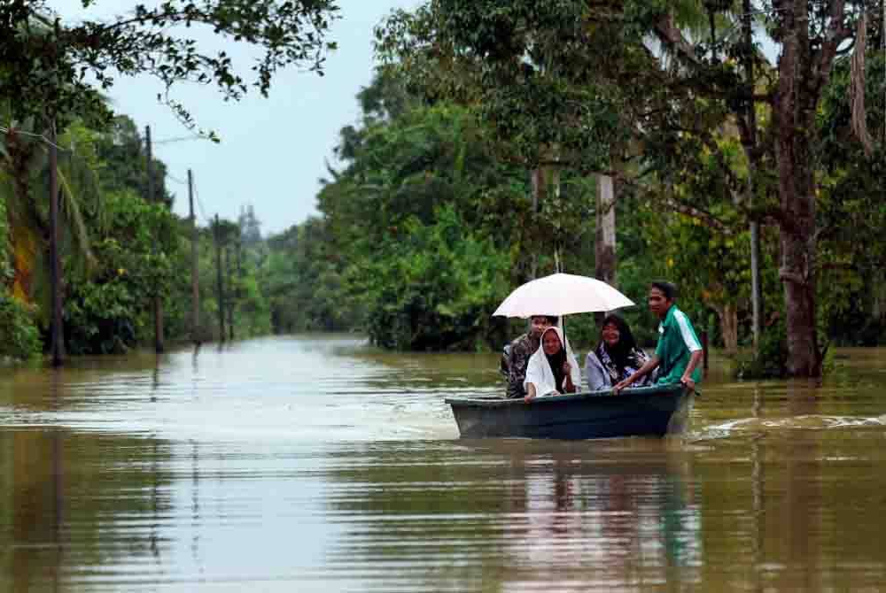 Penduduk kampung menggunakan bot untuk keluar ke jalan utama yang masih terputus akibat banjir di Kampung Delong - Foto: Bernama