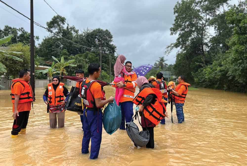 Anggota penyelamat membantu memindahkan penduduk yang terjejas banjir. Foto APM