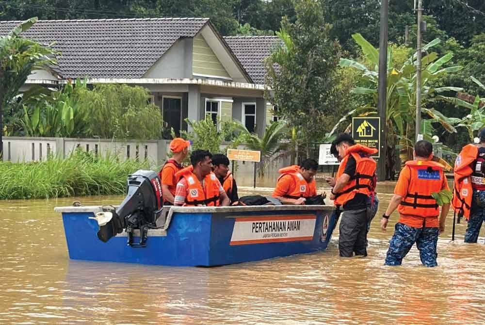 Anggota penyelamat membantu memindahkan penduduk yang terjejas banjir. - Foto Angkatan Pertahanan Awam Malaysia (APM)