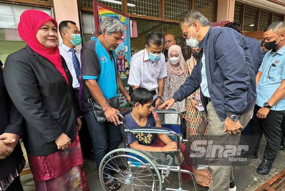 Dr Dzulkefly (kanan) melihat keadaan seorang kanak-kanak, Adam Mamat yang berkerusi roda kerana kemalangan jalan raya dua bulan lalu ketika lawatan di PPS SK Jeli pada Ahad.