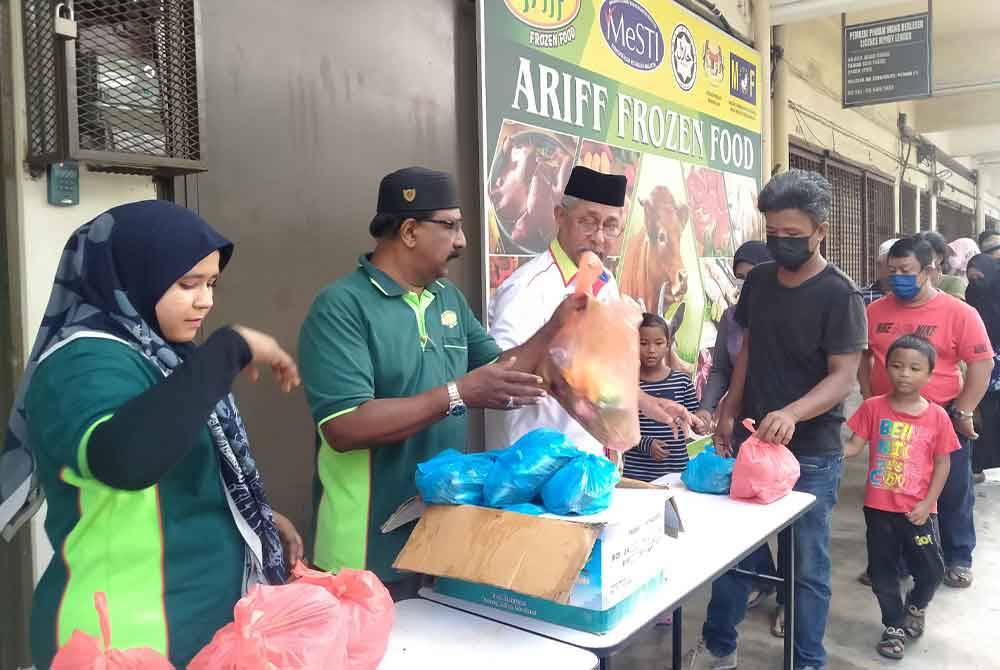 Mohamed Arib (dua dari kiri) membantu mengedarkan barang-barang keperluan sempena Program Dapur Rakyat Ambang Tahun Baharu di pekarangan Ariff Frozen Food, Taman Seri Tasek di sini pada Ahad.