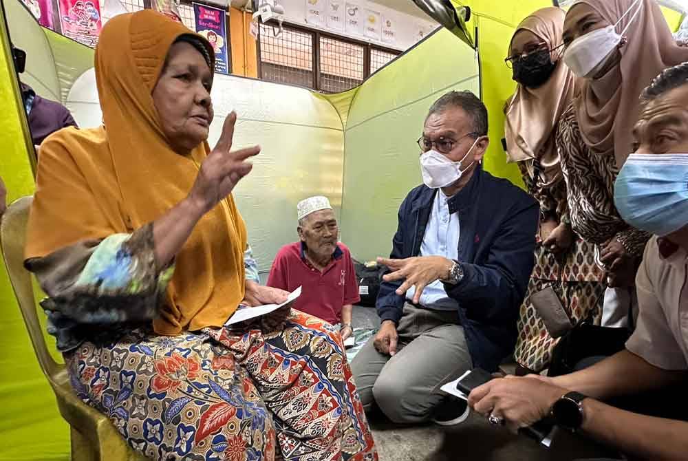 Dr Dzulkefly (tengah) mendengar luahan Minah Omar, 85, (kiri) berkaitan rumahnya yang ditenggelami banjir di Kampung Jeli Bawah, Pekan Jeli Lama, Jeli.