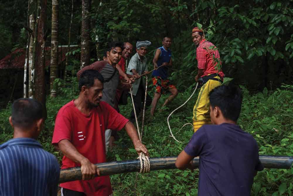 Penduduk Kampung Lata Janggut bergotong royong membaiki paip air tandak (air tadahan bukit) yang terputus dan jatuh ke kawasan sungai akibat tanah runtuh di laluan masuk ke perkampungan tersebut Jumaat lepas, ketika tinjauan pada Ahad. - Foto Bernama