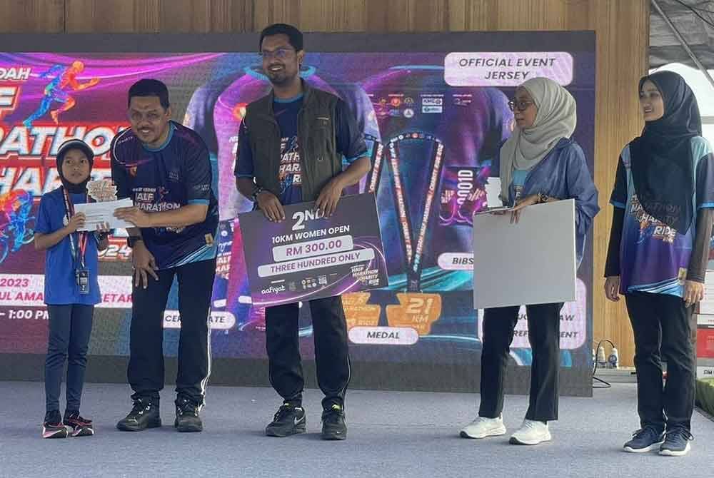 Muhammad Radhi (dua dari kiri) menyampaikan hadiah kepada peserta Program New Year Kedah Half Marathon & Charity Ride 2024 di Stadium Darul Aman.