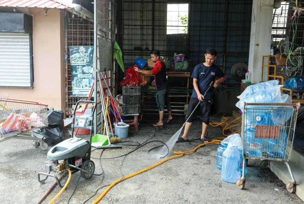 Pembantu kedai Mohamad Syafiq Mat Saleh bersama Muhd Syawal Aqib Aminuddin (kanan) membersihkan kedai yang dinaiki air selepas banjir melanda kawasan Kampung Ana ketika tinjauan pada Ahad. Foto Bernama