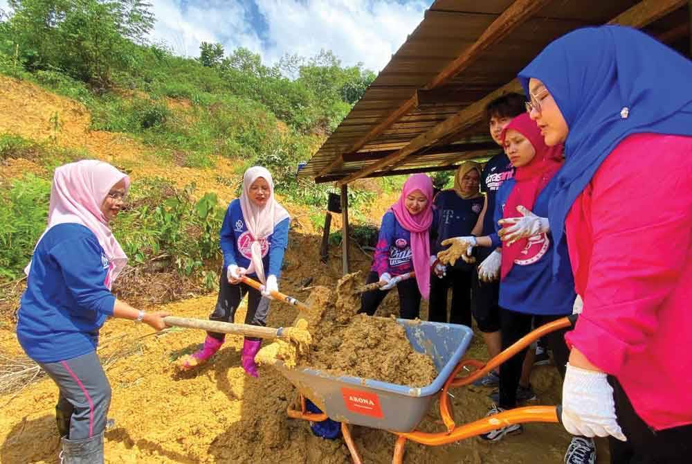 Nurul Amal (dua dari kiri) bergotong-royong bersama sukarelawan Puteri UMNO membersihkan rumah penduduk yang rosak dihempap tanah runtuh di Kampung Dalam Reka, Jeli pada Isnin.