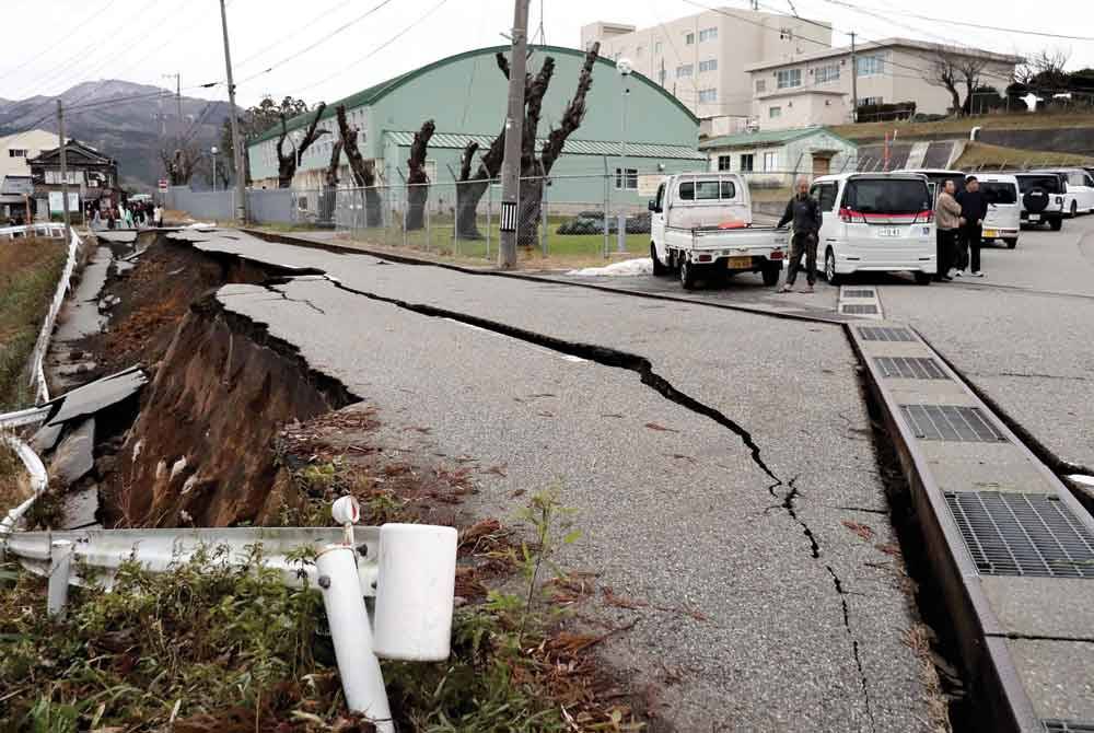 Orang ramai berdiri di sebelah jalan yang retak selepas gempa bumi berukuran 7.5 magnitud melanda wilayah Noto di wilayah Ishikawa pada Isnin. - Foto: AFP/ Yomiuri Shimbun